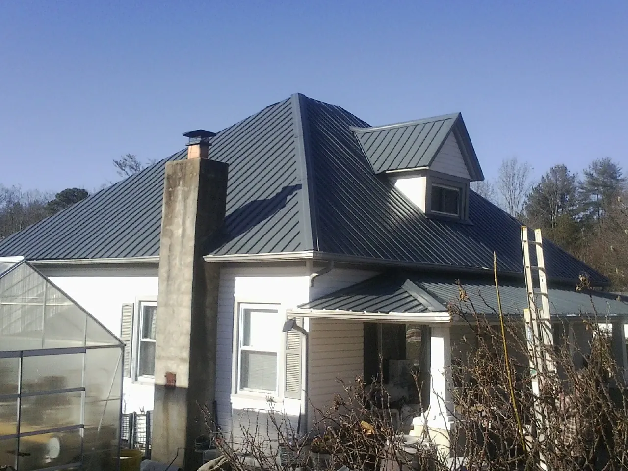 Dark blue standing seam metal roof on a white farmhouse with dormer — Slate & Tile Roof Repair by Roofing Brothers in Fleetwood