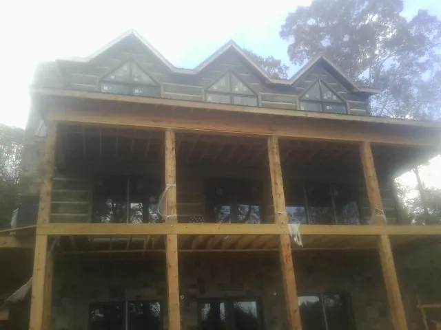 Dormers and porch framing on a large log home under construction — Roof Coating work by our crew in Fleetwood