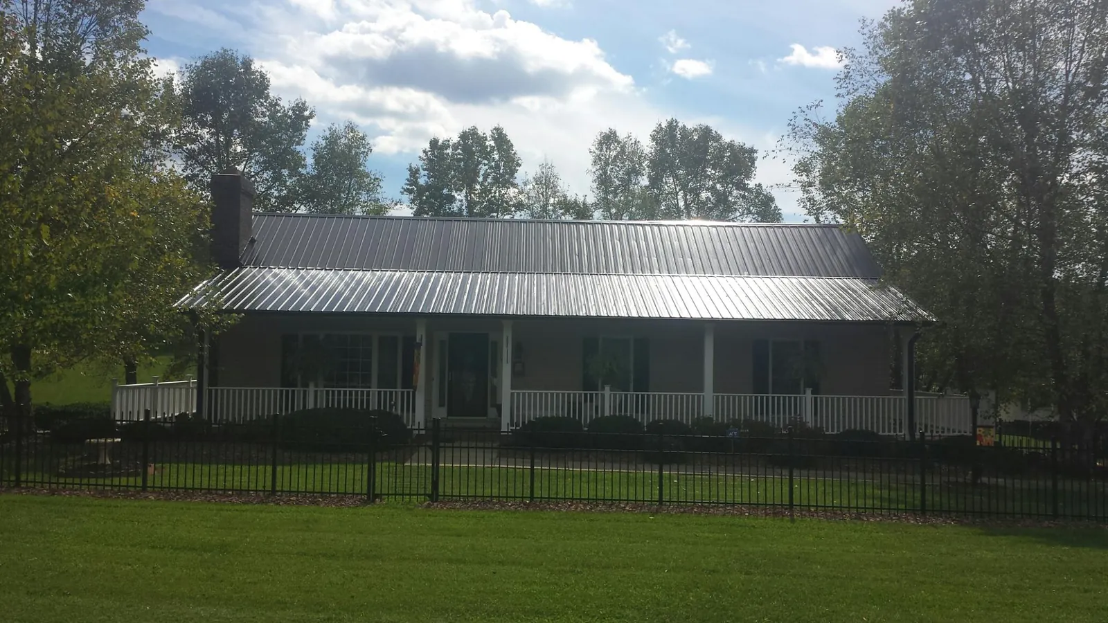 Gray metal roof on a brick ranch with a full width front porch — Gutter Guard Installation work by our crew in Fleetwood