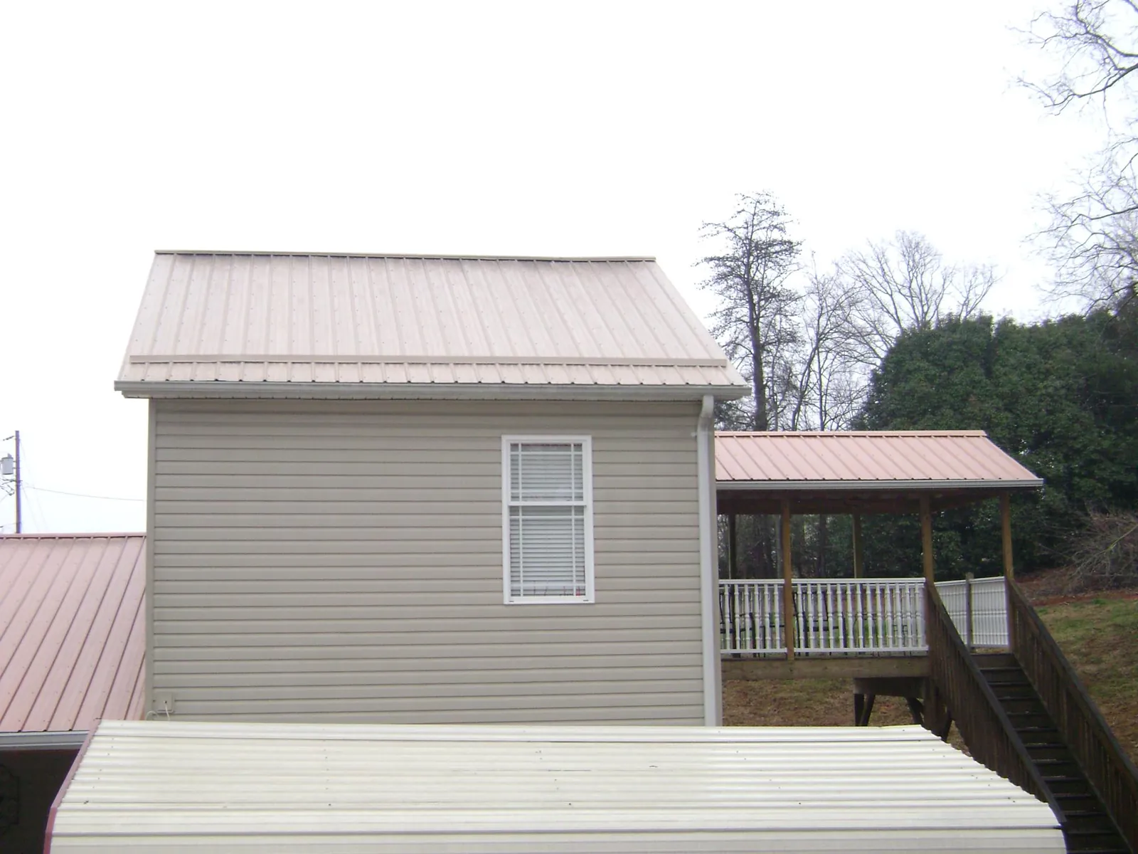 Tan metal roofs on a two story addition and attached porch, from a Roof Replacement job in Fleetwood